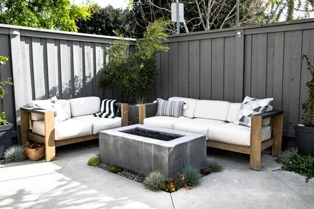 Modern backyard with outdoor sofa seating and a concrete fire feature