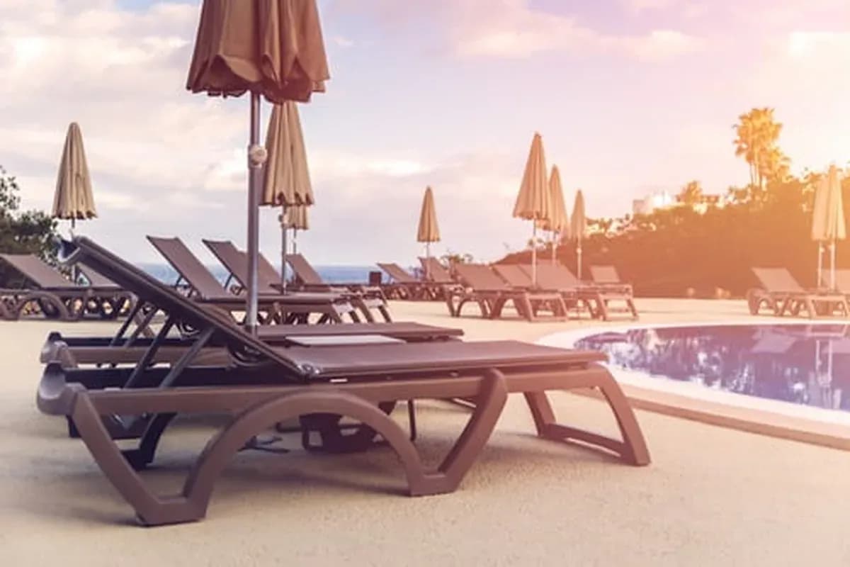 Pool lounge chairs beside the water at sunset