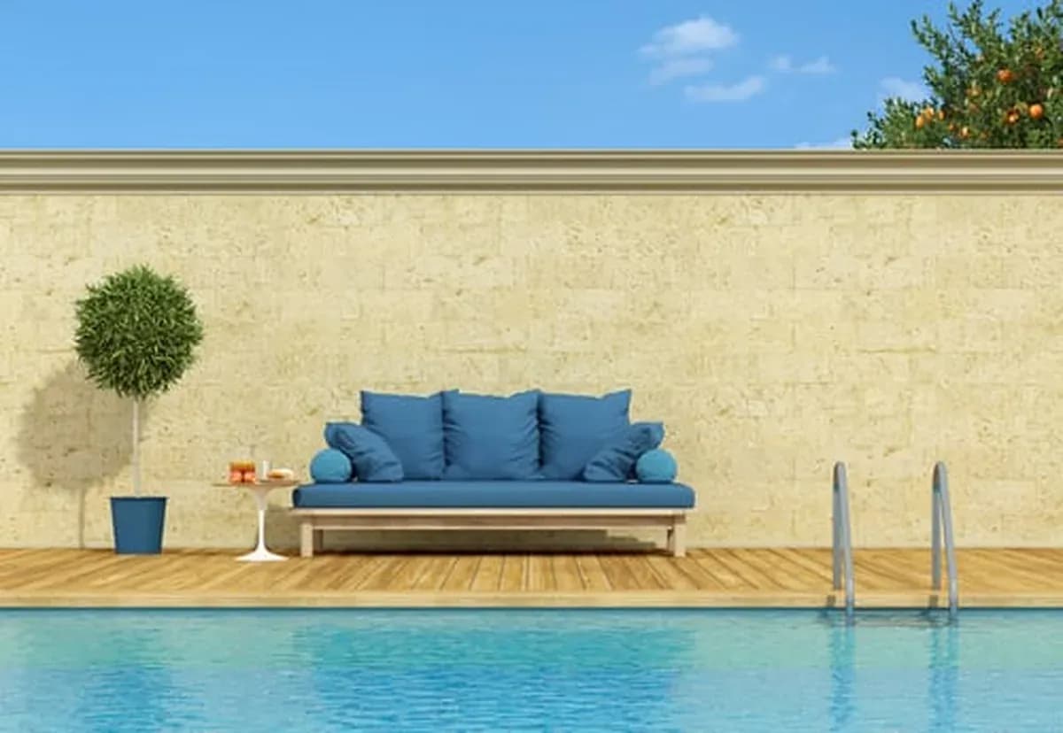 Poolside lounge sofa beside a calm blue swimming pool