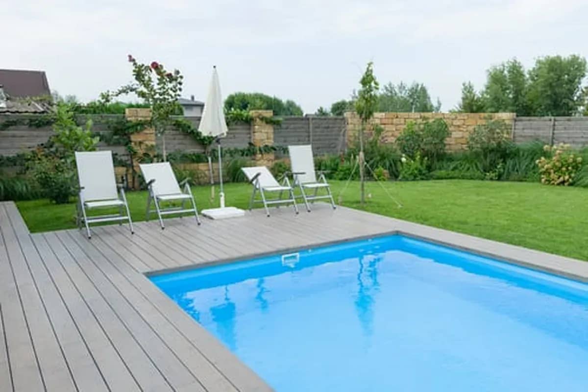 Newly constructed backyard swimming pool with composite decking and lawn
