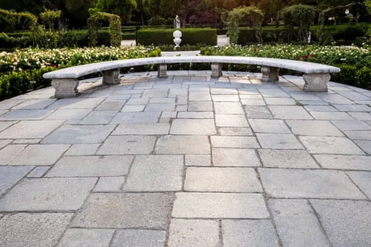 Large-format stone paver patio with a curved garden bench