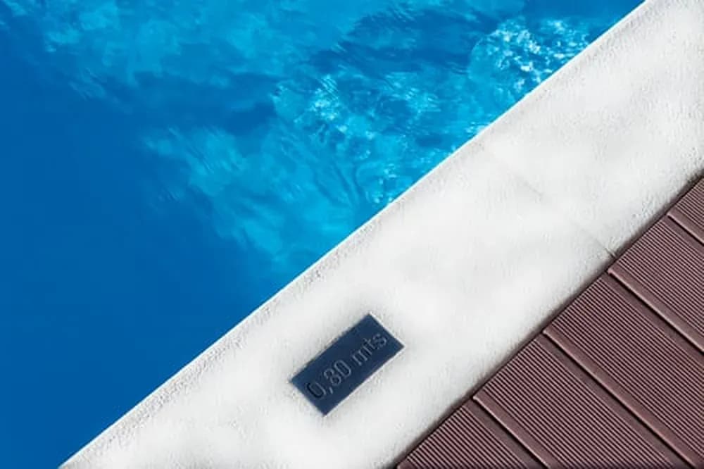 Close-up of a pool corner showing white coping and deep blue water