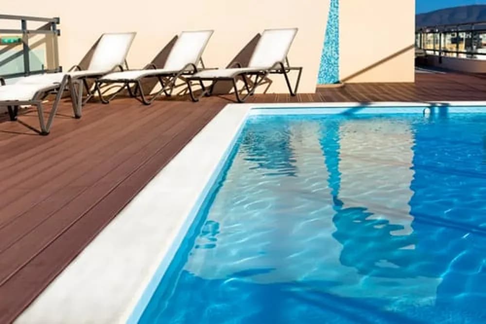Finished pool deck with lounge chairs beside clear blue water